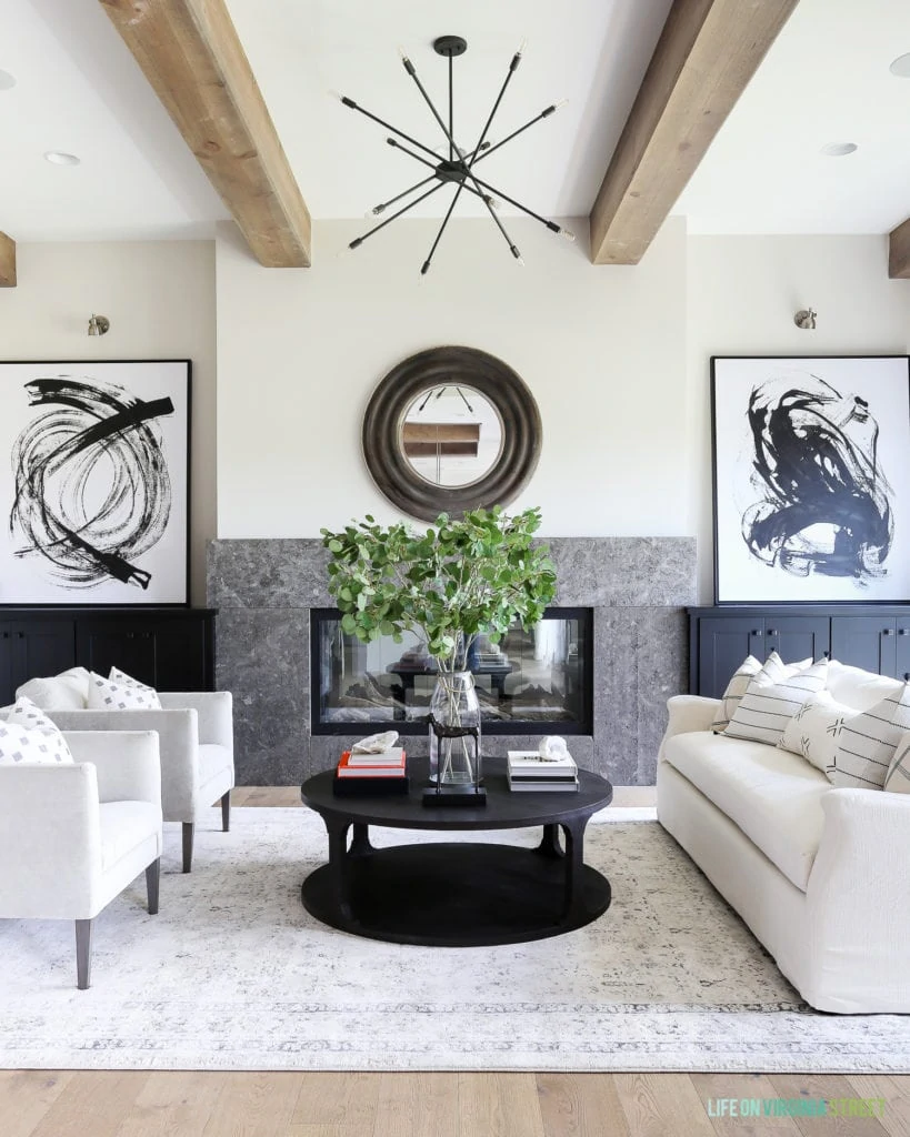 A California Modern Farmhouse from the 2018 Omaha Street of Dreams. I love the combination of natural wood beams with modern details like the sputnik chandelier and graphic black and white artwork. The linen sofa is accented with black and white mudcloth pillows.