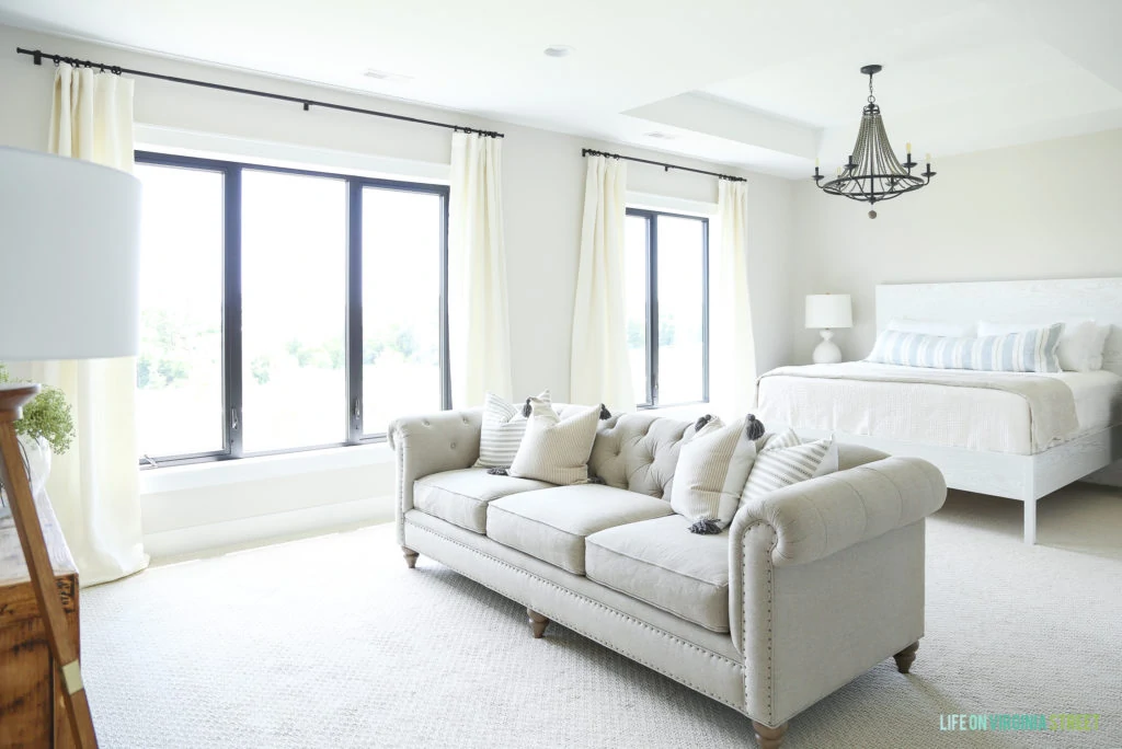 Master bedroom in a white neutral color with a white sofa in the middle of the room.