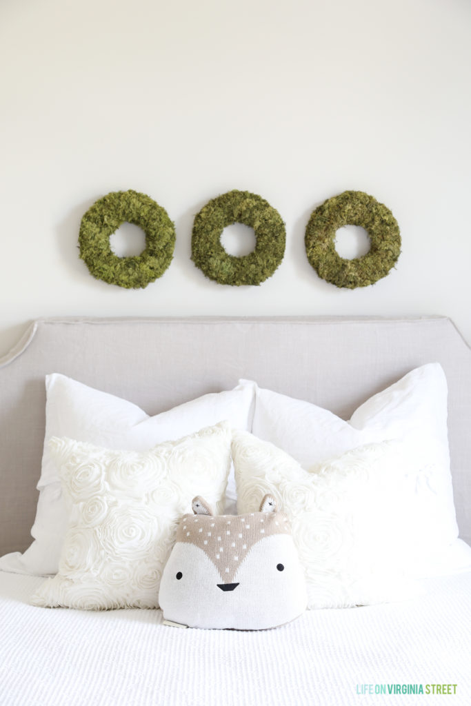 A close up view of the three mossy green wreaths above the bed.