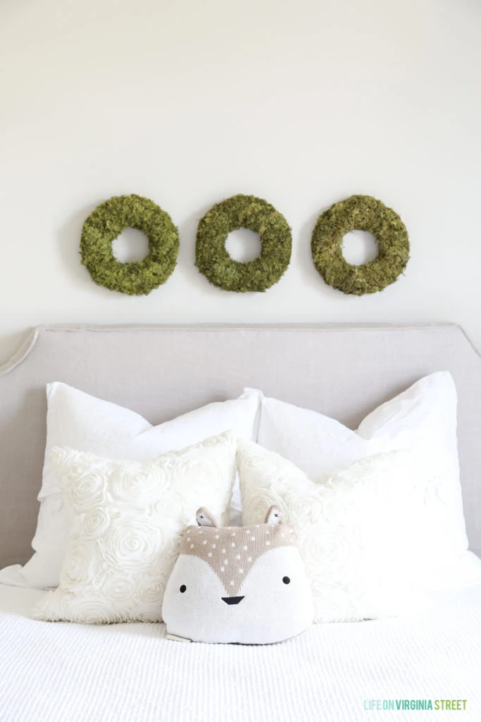 A close up view of the three mossy green wreaths above the bed.