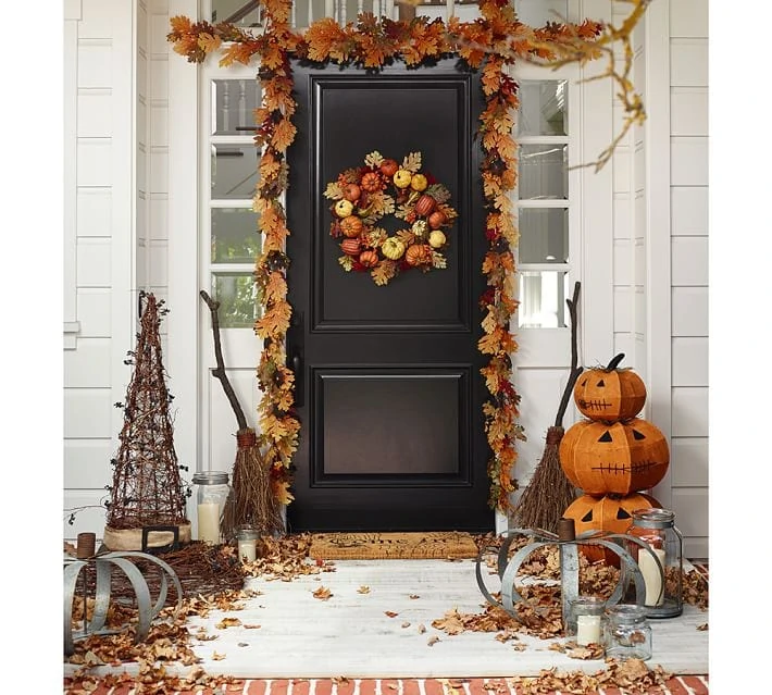 A fall porch with Halloween accents, and red, brown leaves.