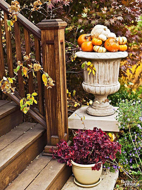 An ornamental planter at the foot of the stairs filled with mini pumpkins.