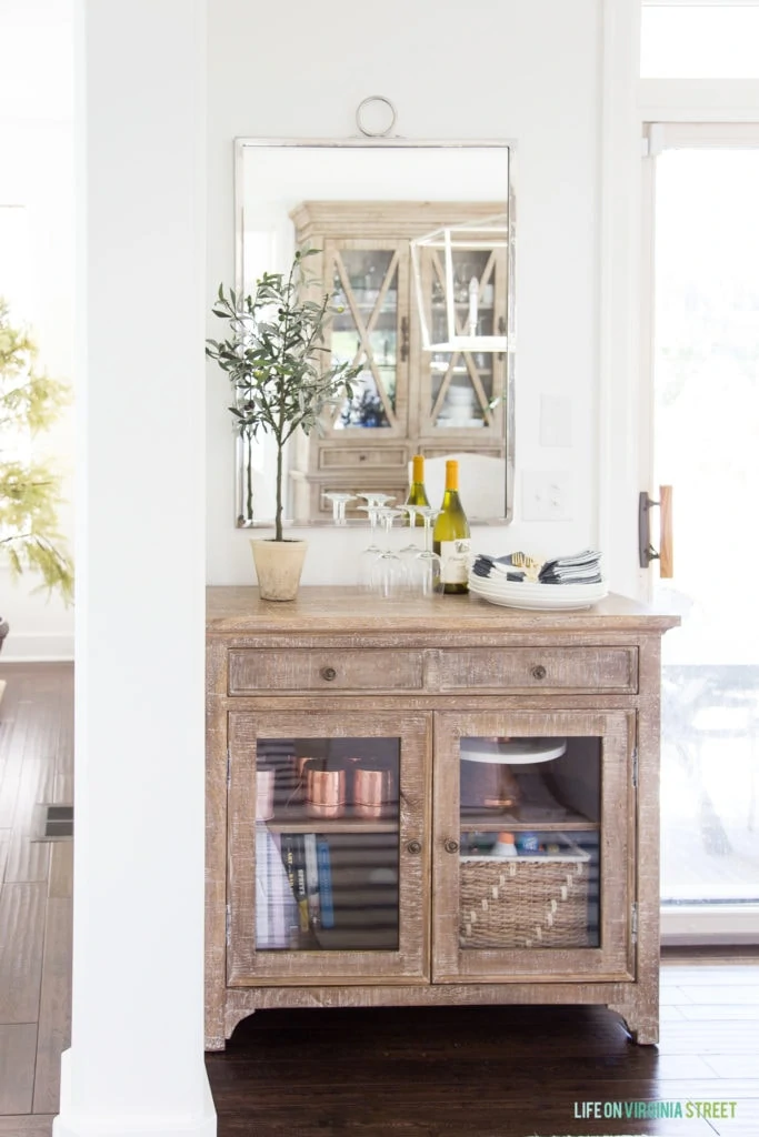 A distressed wooden buffet with a plant on it and a mirror hanging above it.