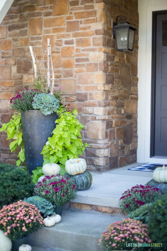 Pumpkins, large planter filled with kale, and purple and pink flowers all on the front porch.