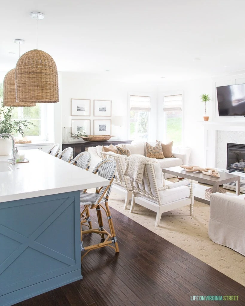 Blue kitchen island with the sitting room behind it, in a white coastal decor.