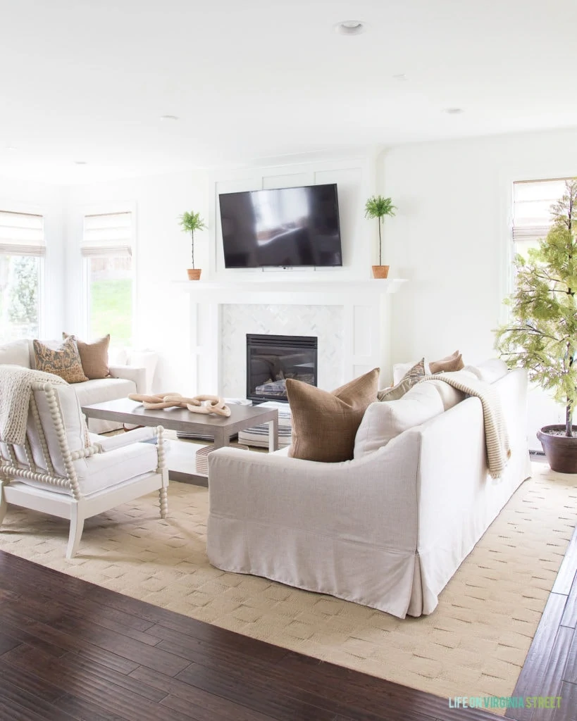 Gorgeous neutral fall living room with natural accents and shades of brown and white. I love the spindle chair, linen sofas and cypress tree!