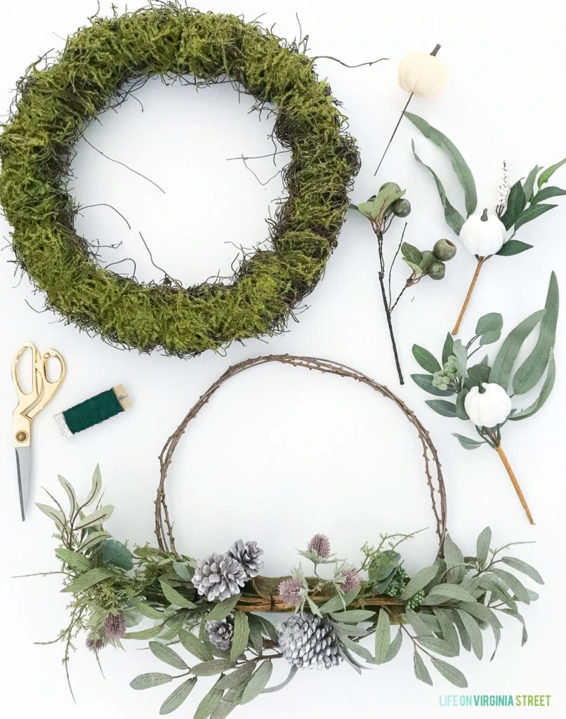 Green moss wreath and leaves with purple pinecones.