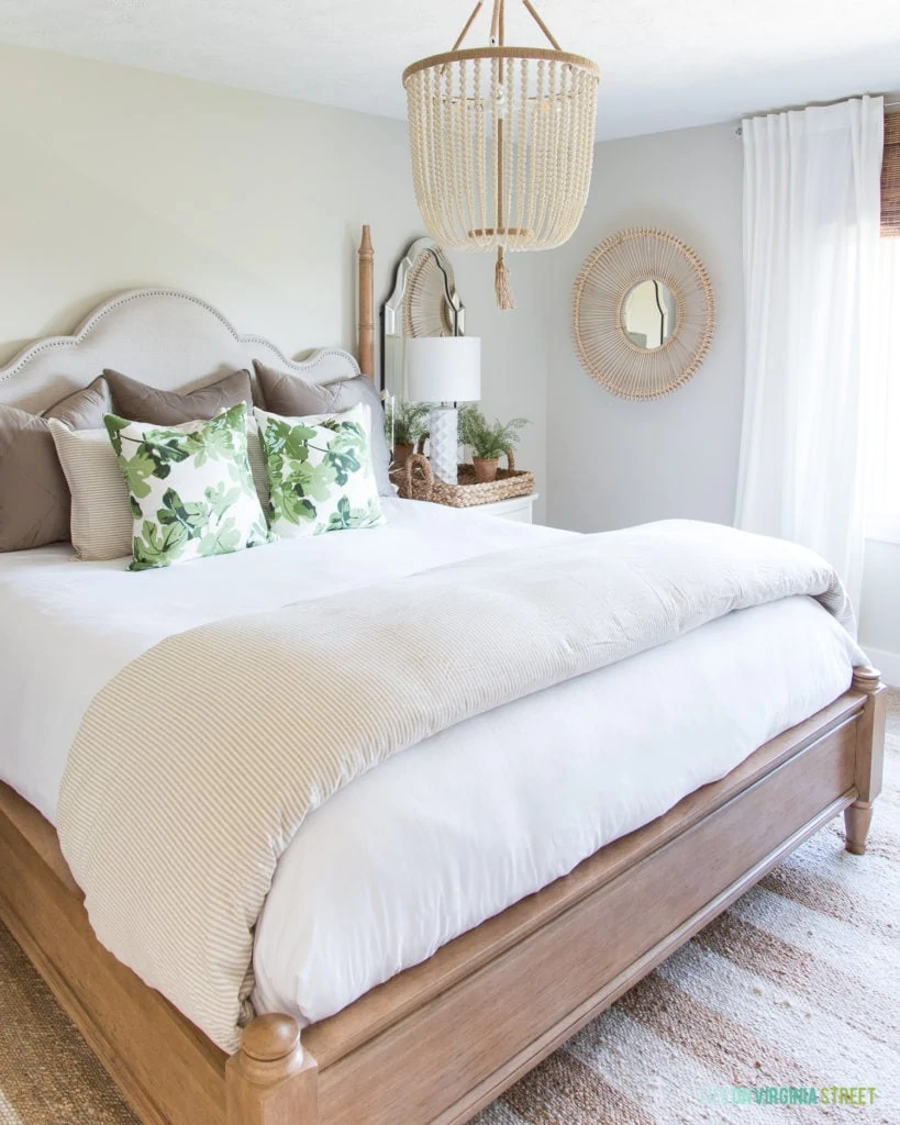 A cozy neutral fall bedroom with a beaded light hanging over the bed.