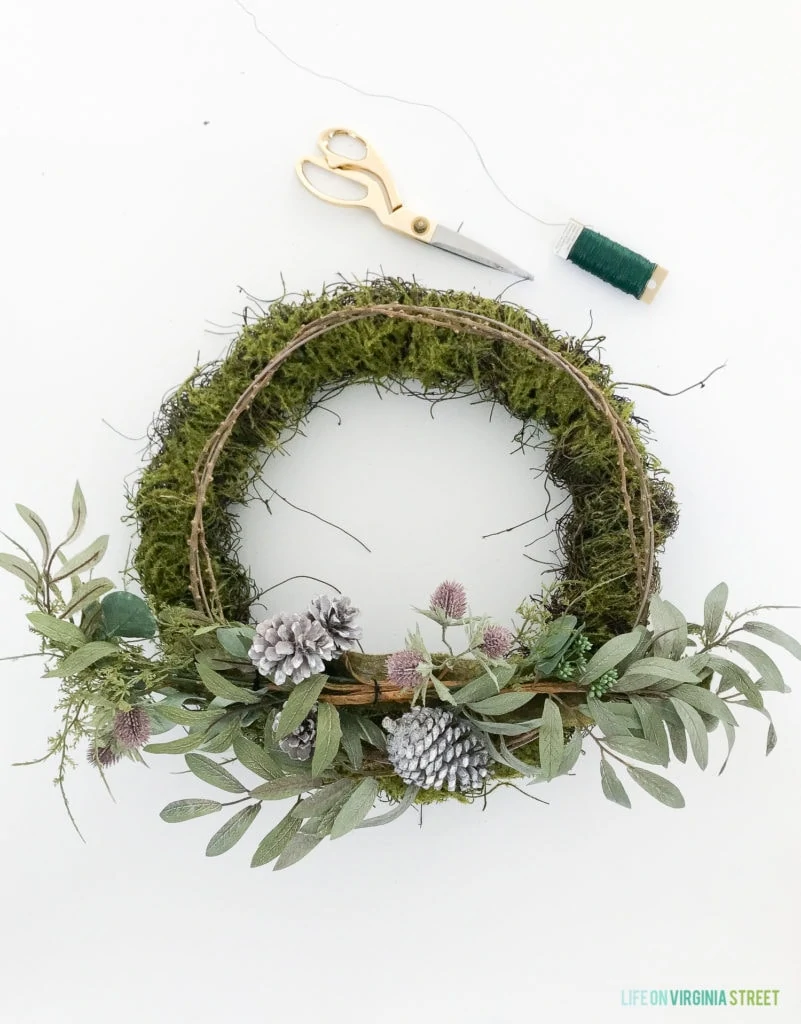 Putting the wreath together, pictured scissors and thread and the green wreath.
