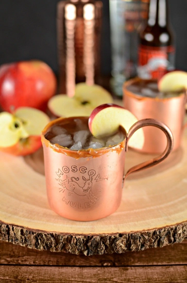 Apple cider Moscow Mule in a copper cup and an apple slice on rim.