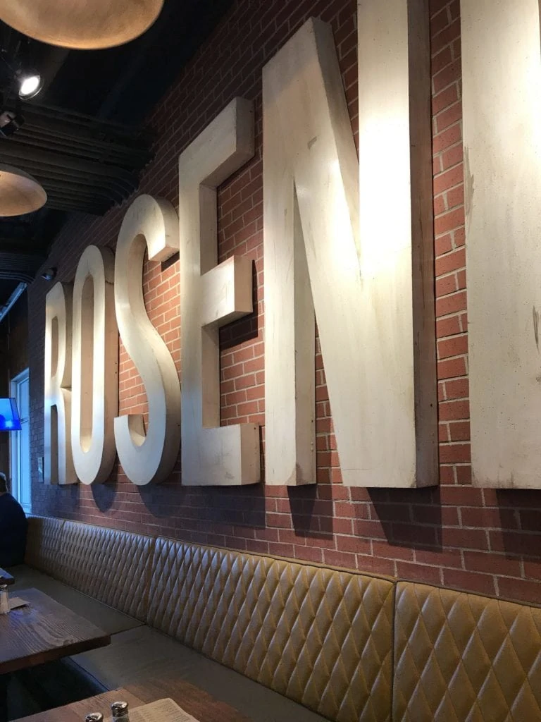 The inside of a pub that has brick walls and a long banquet seating.