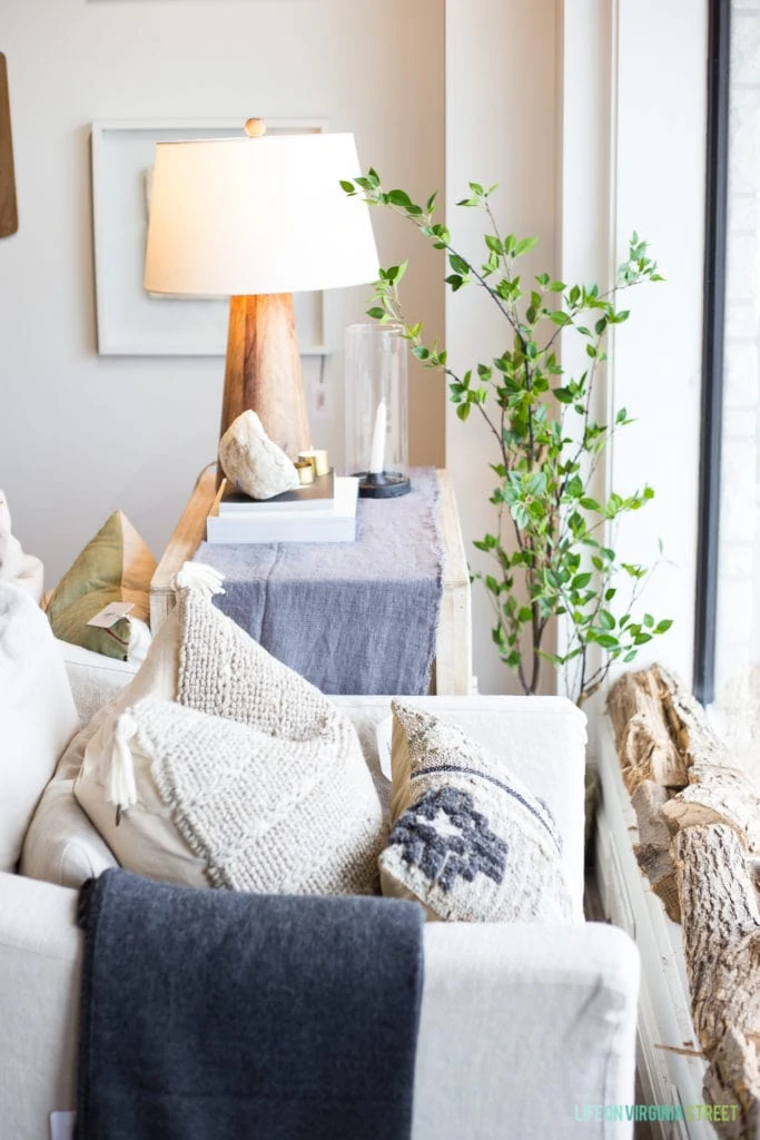 A white couch with neutral pillows and blue blankets in shop.