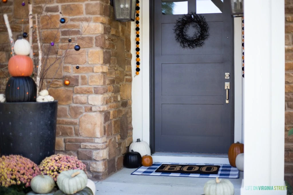 The front door with a black wreath on it and a boo welcome mat.