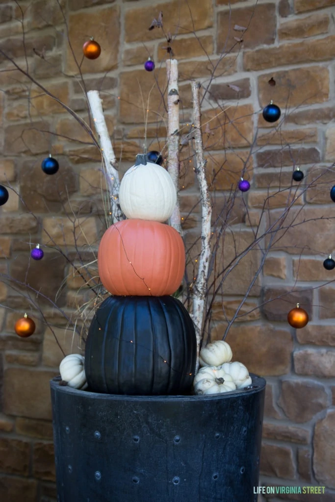 The funkin pumpkins in a black planter with decorated branches of purple gold and blue baubles.