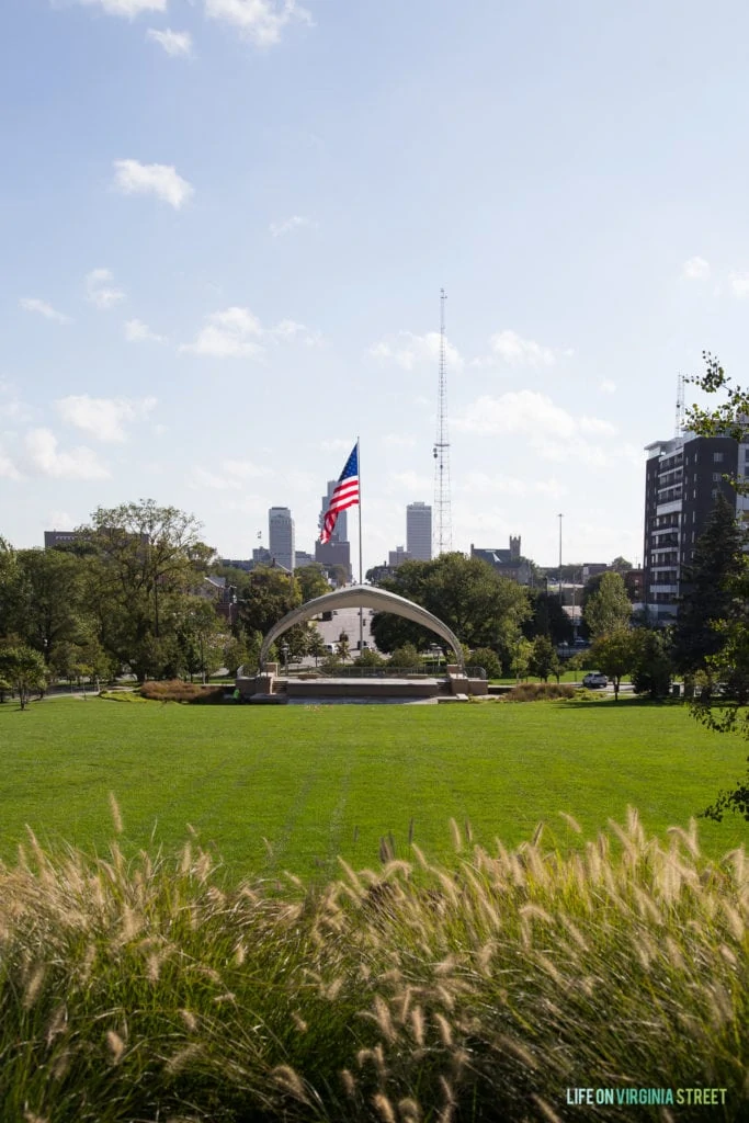 A large park with a monument in the centre and an American flag.