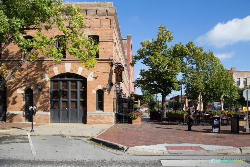 A marketplace with large wrought iron doors and large green trees in front of it.