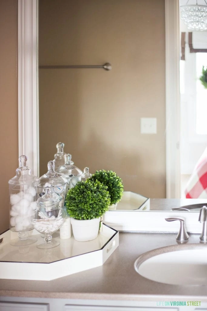 Guest bathroom with small green topiaries beside the sink.