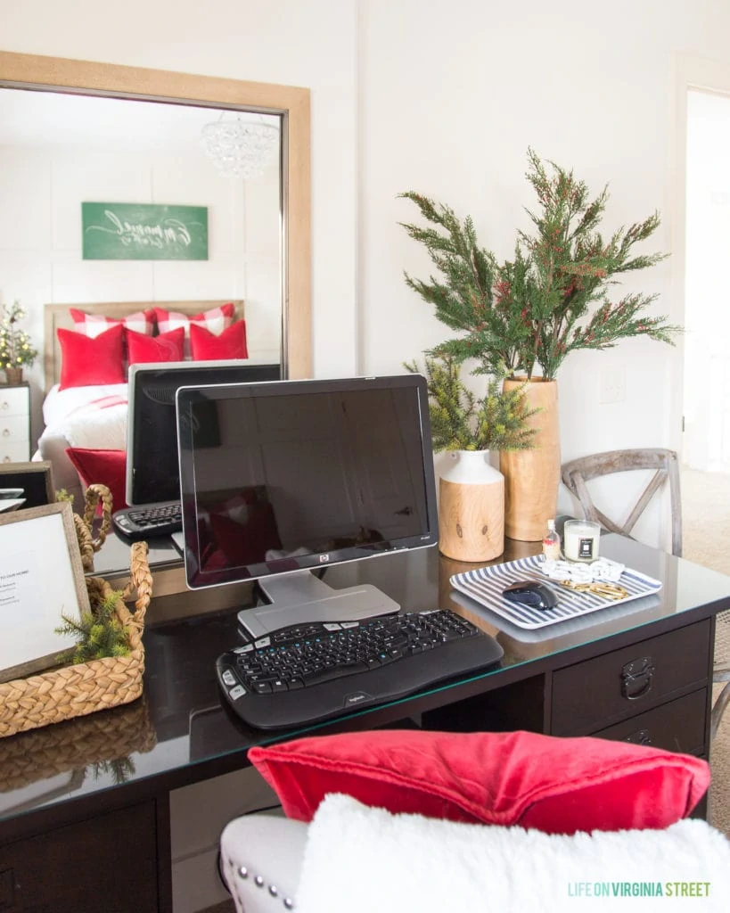 Computer on the desk with greenery in a vase beside it.