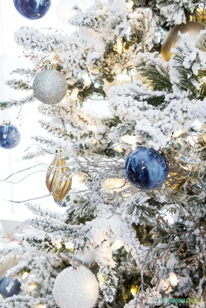 Up close picture of white, gold and blue ornaments on Christmas tree.