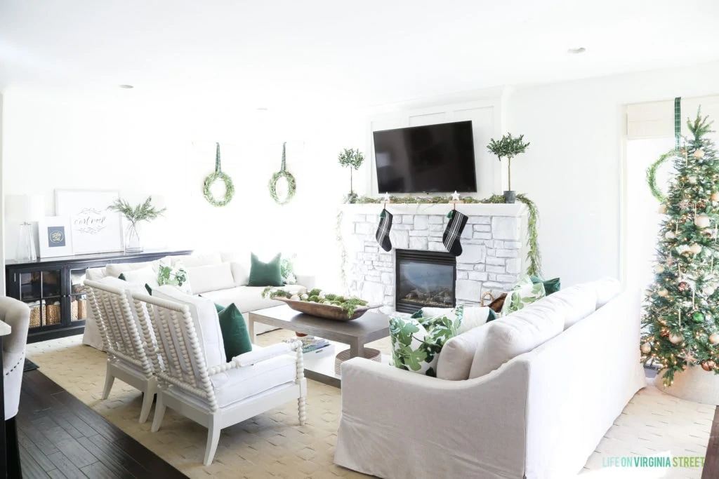 A beaded Christmas tree collar in a white and green Christmas living room.