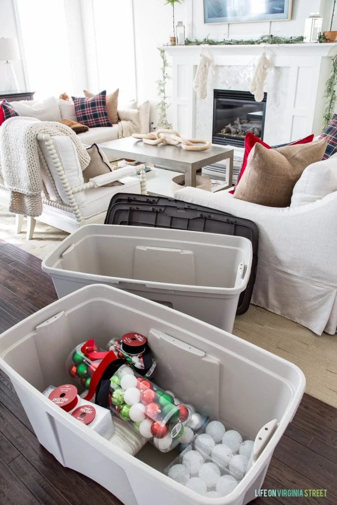 Neutral living room with Christmas ornaments in a plastic bin.