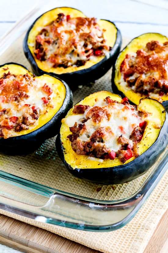 Cheesy Sausage And Pepper Stuffed Acorn Squash in a clear glass baking dish.