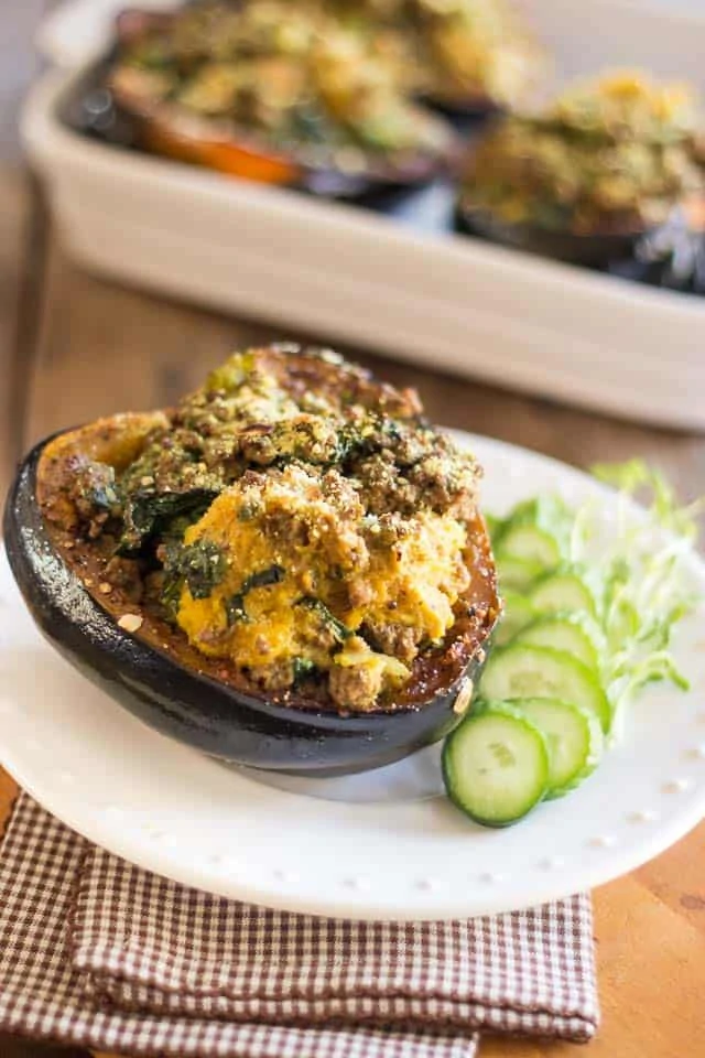 A baked ground beef squash on a plate with cucumbers beside it.