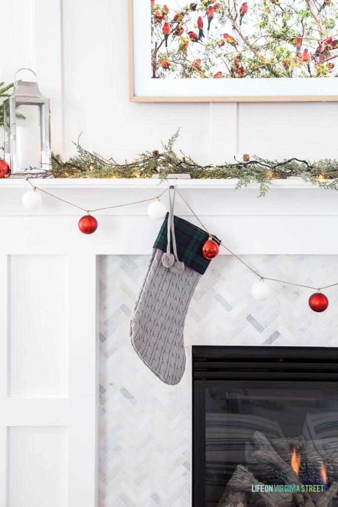 A simple Christmas mantel with a DIY ornament garland and red, white and green accents.