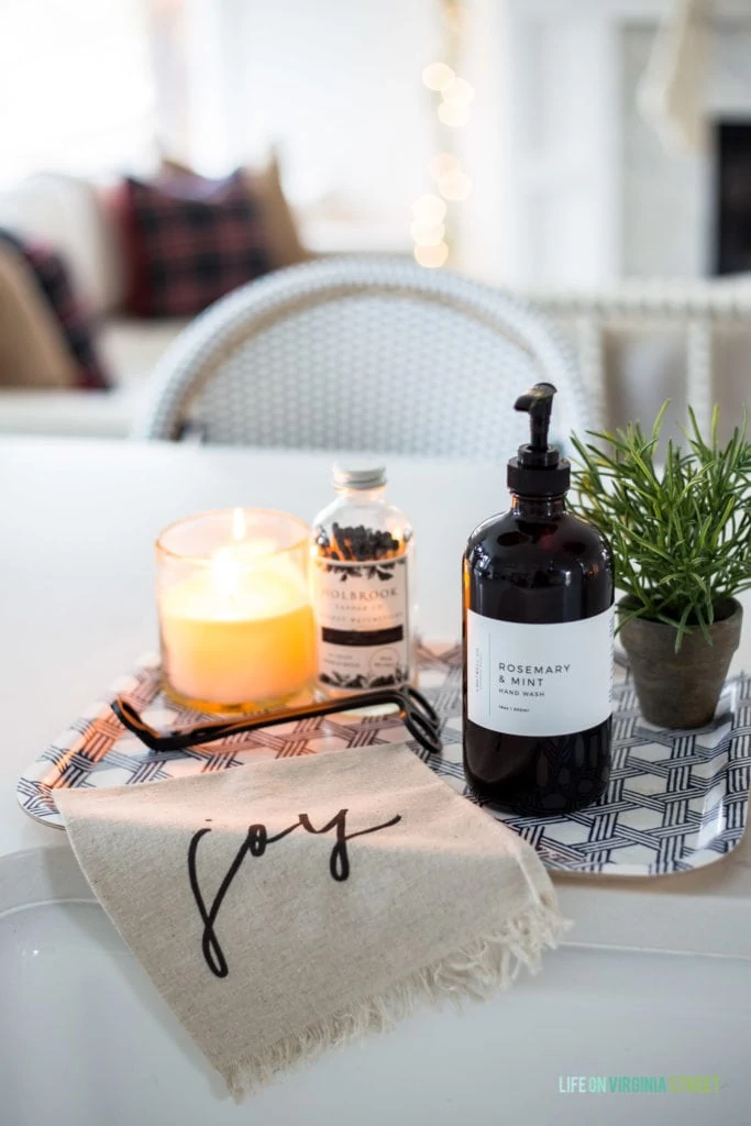 A Christmas sink with greenery, candles, wick trimmer, and a 'joy' towel.