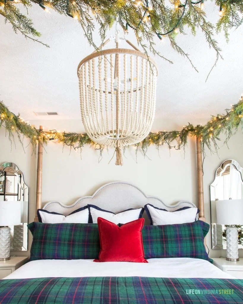 Such pretty plaid Christmas decor bedding in this holiday bedroom! I also love the white bead chandelier and the red velvet pillow on the canopy bed!