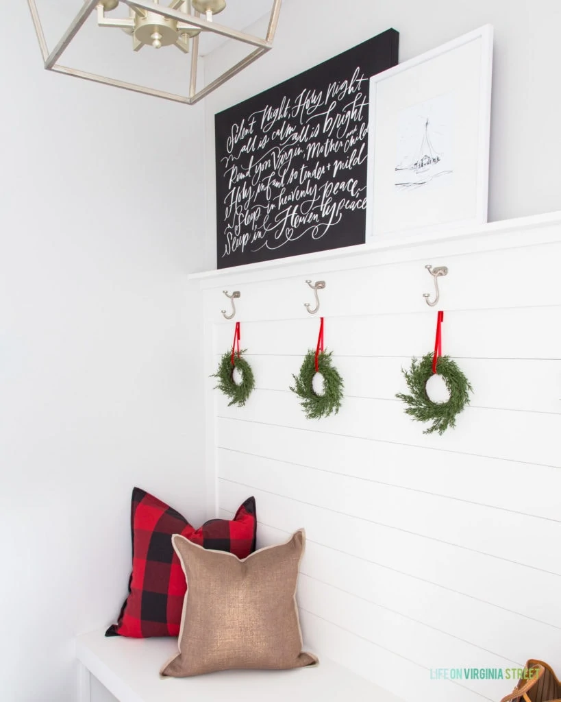 A cute mudroom decorated for Christmas! I love the half shiplap wall and hooks!