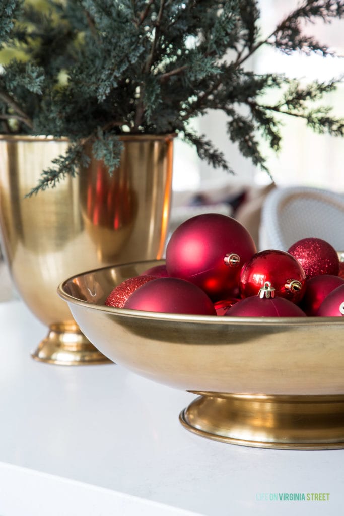 A gold metal bowl filled with red ornaments and a gold vase filled with faux juniper greenery stems! I love these simple Christmas decorating ideas!