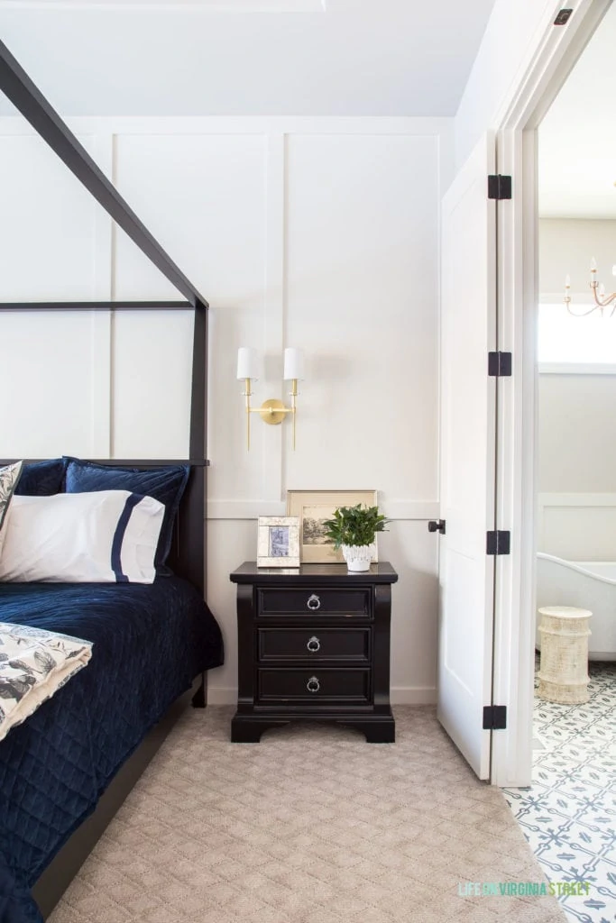 White board and batten painted Benjamin Moore Cloud Cover. Bedroom features a canopy bed, navy blue linens, and gold sconces.