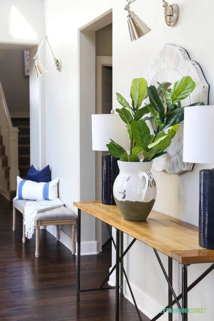 Faux fiddle fig stems in a terra cotta vase styled in an entryway hallway. A great and more budget-friendly alternative to a fake fiddle leaf fig tree!