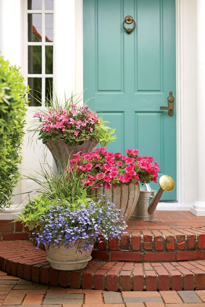 Summer porch planter ideas. These pink geraniums, petunias, and purple lobelias look so beautiful paired with the turquoise front door!