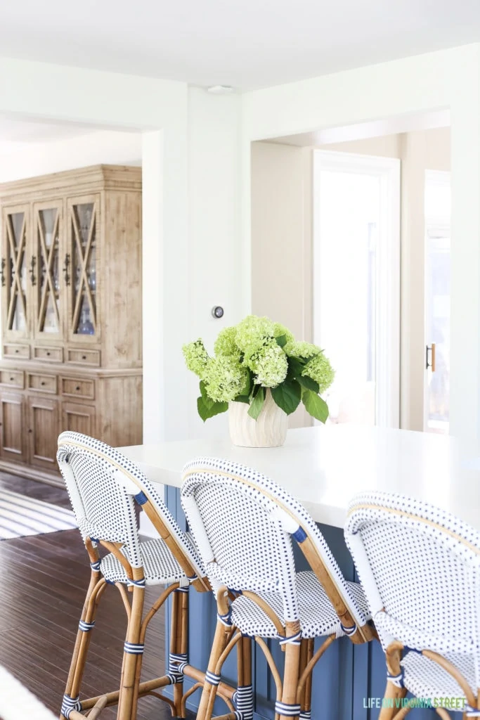A kitchen island with hydrangeas on the top and chairs around it.