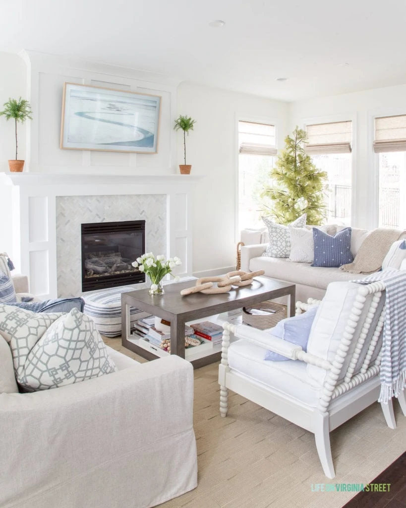 A spring living room with blue and white stripes and faux green topiaries. 