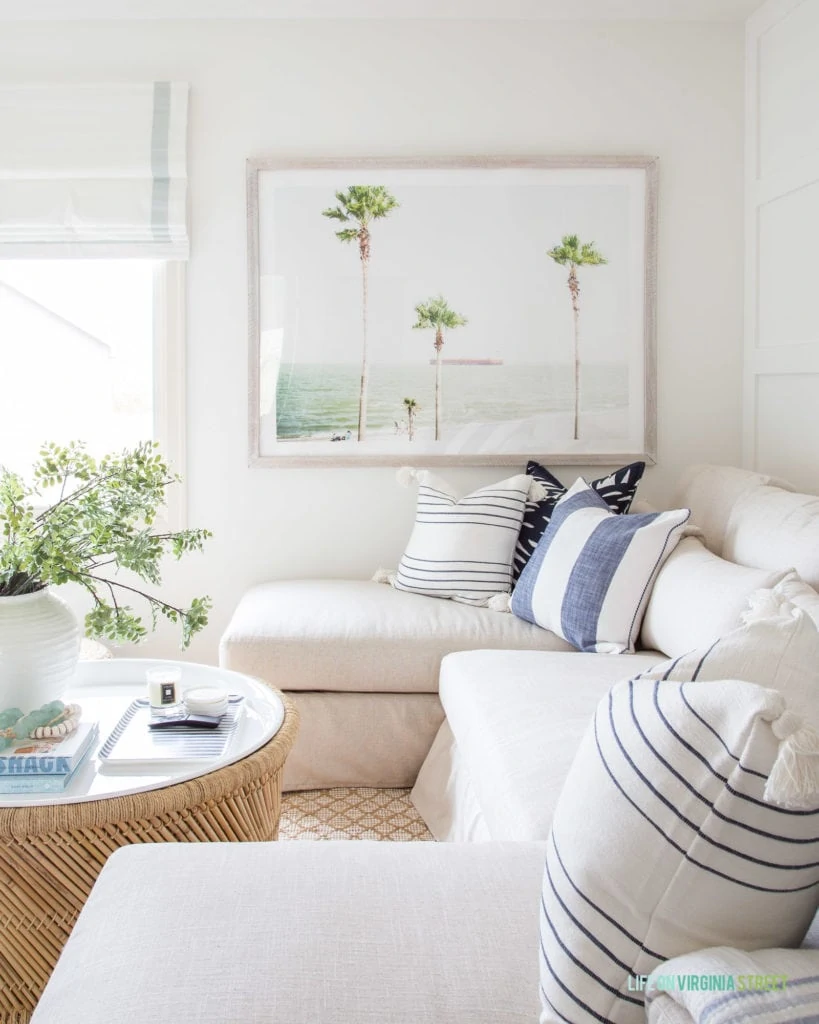 Palm tree art in a coastal den design. I love all of the blue, white and neutral accents in this TV room!