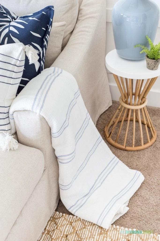A blue and white striped gauze blanket draped over the arm of the sectional couch.