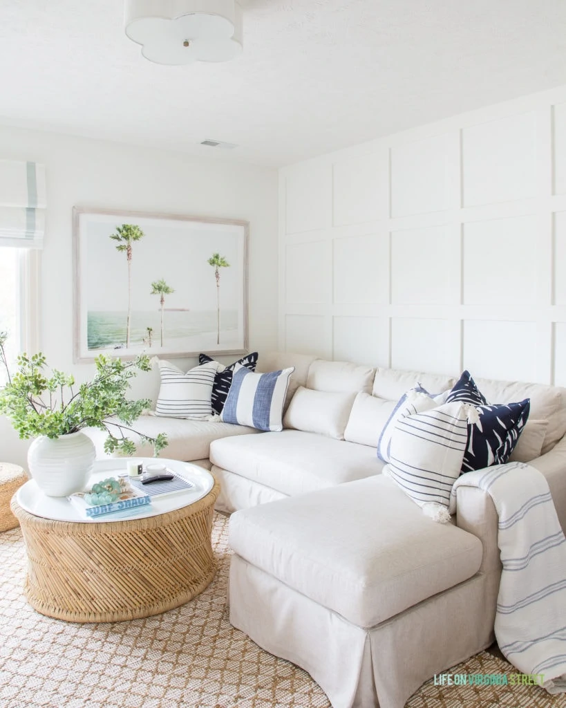 A white sectional sofa with blue and white pillows and a small coffee table.