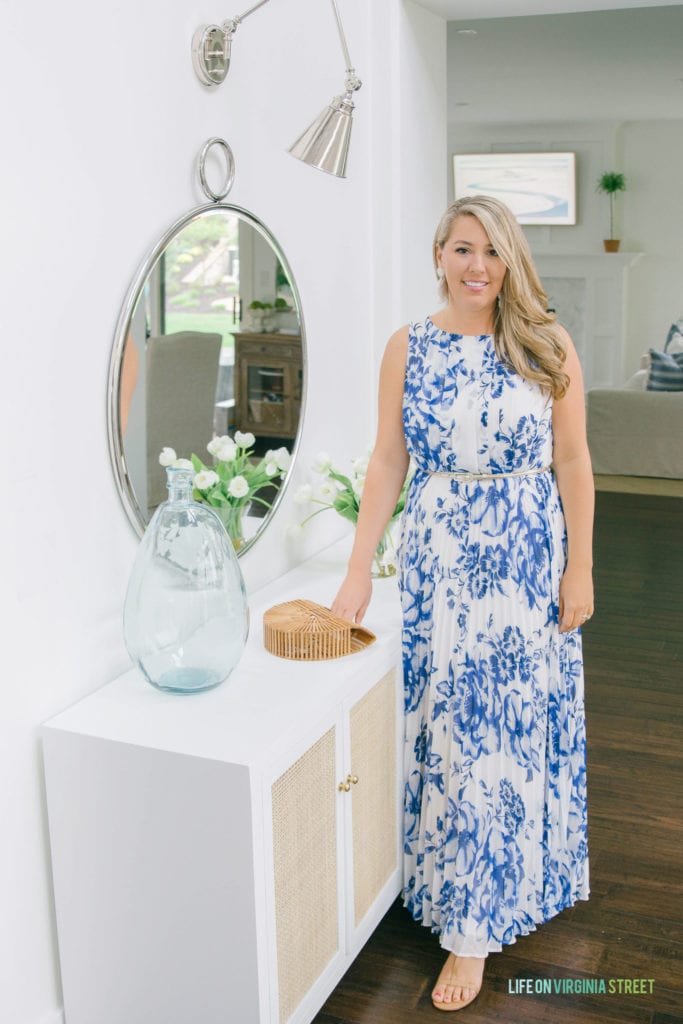 A blue and white floral dress modelled by a woman standing in front of a hallway mirror.
