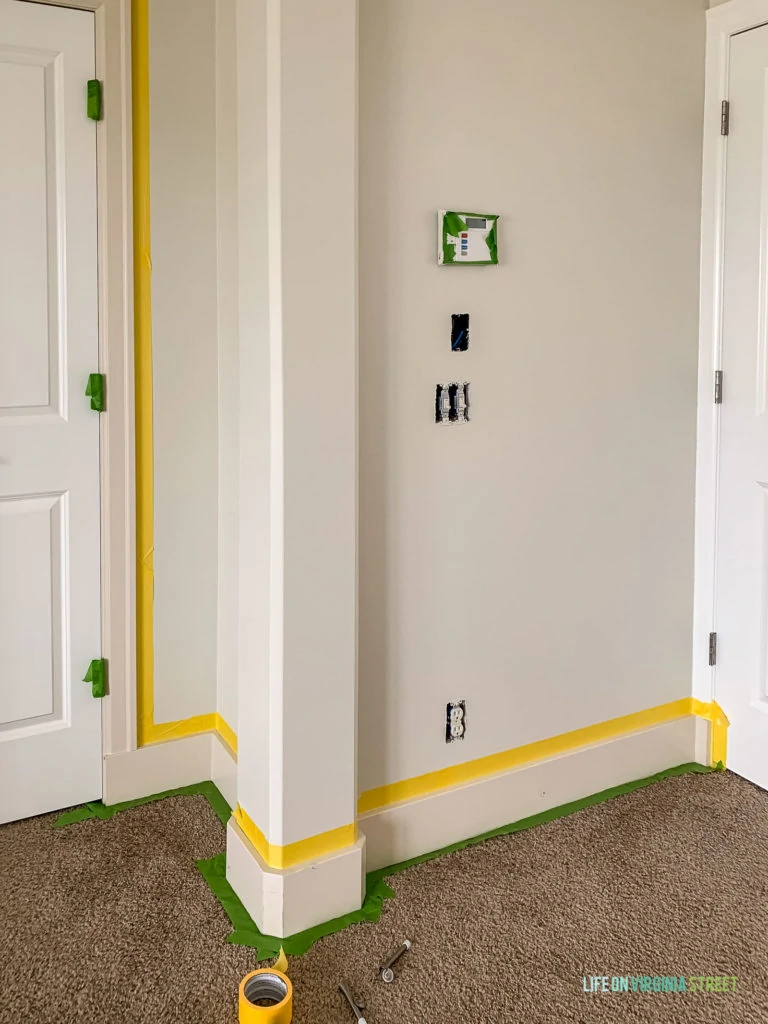 Yellow and green Frogtape on the wall in preparation for painting the baseboards.