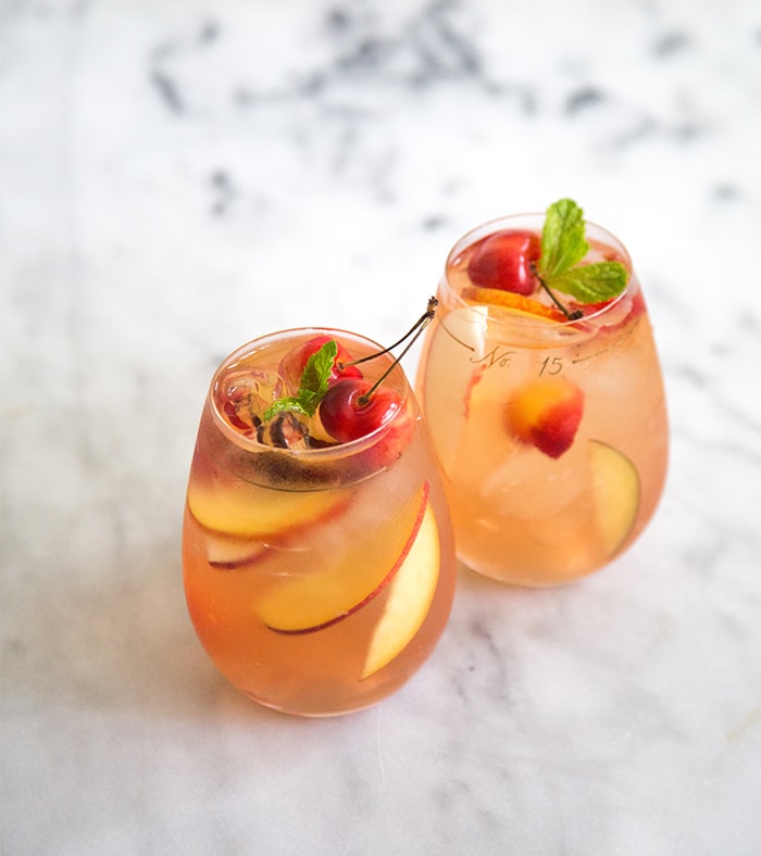 Stone Fruit Sangria with two glasses of sangria and cherries on top.