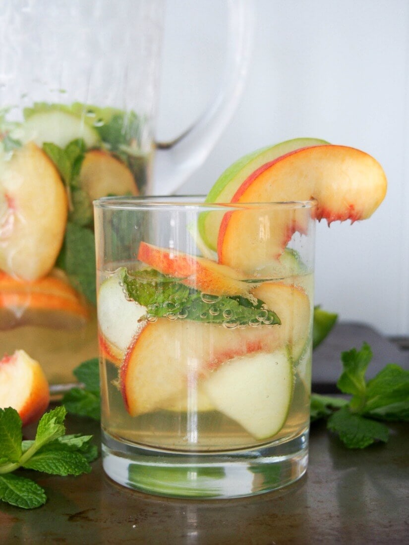  White Sangria With Whiskey, Apples And Peaches are in the cup.