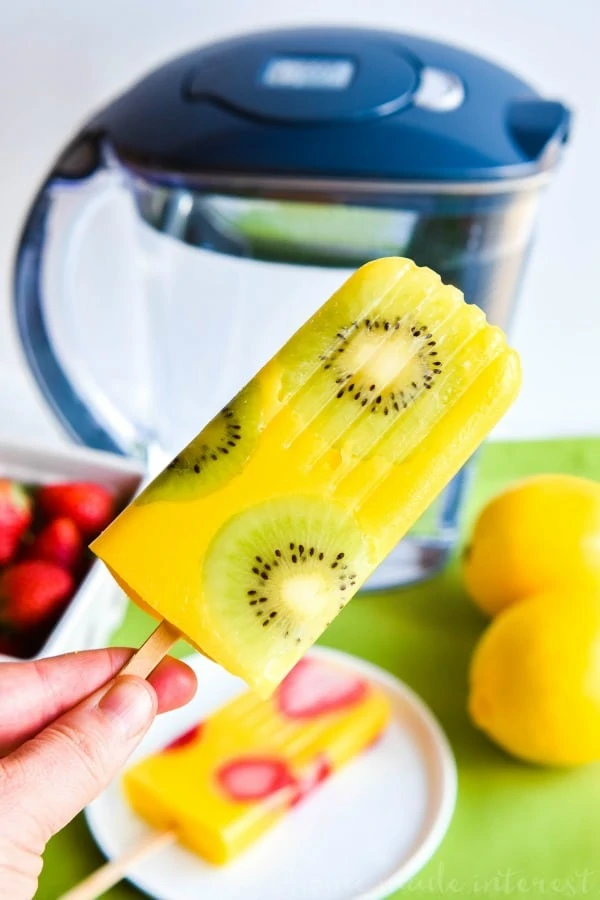 All Natural bright yellow Mango Popsicle being held up.