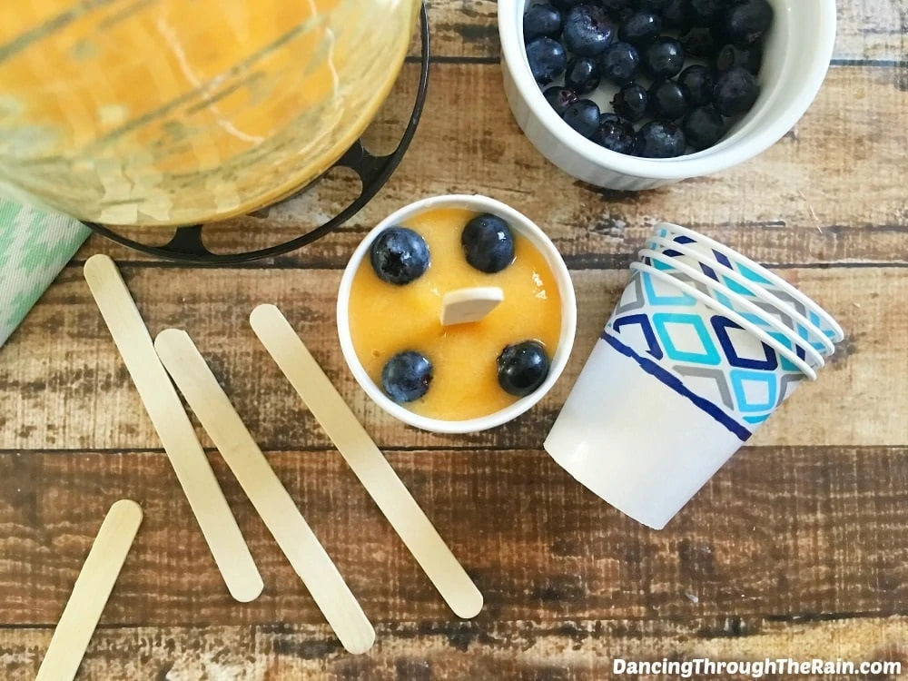 Blueberry Peach Popsicle in paper cups with a wooden popsicle stick.