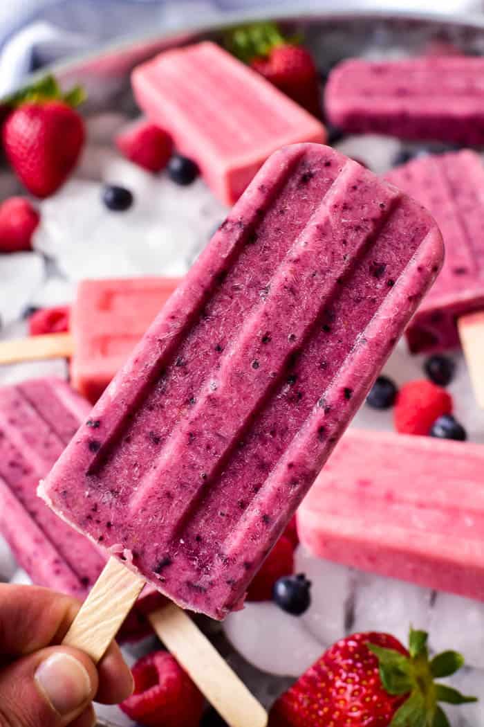 Fruit Smootie Popsicles that are a dark purple in color being held up.
