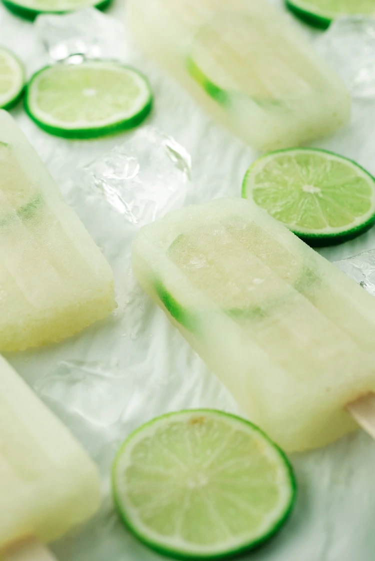 Limeade Popsicles with cut limes beside the popsicles.