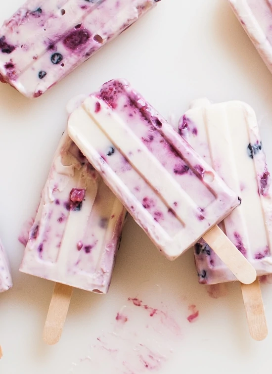 Roasted Berry and Honey Popsicle on a white counter with a berry smear beside it.