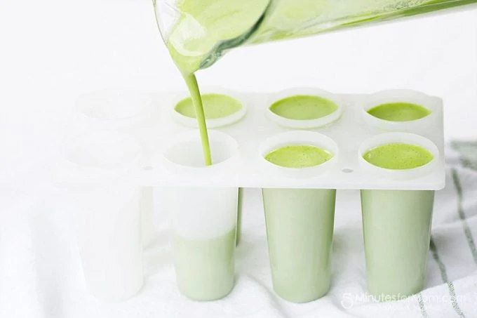 Green smoothie popsicle juice being poured into the popsicle mold.